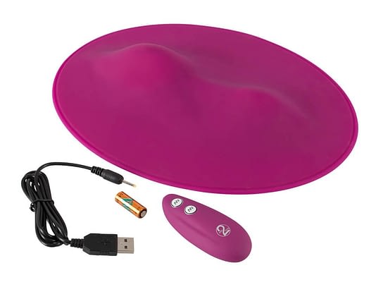 A silicone red pad with two waves appears next to a red remote with two buttons, a battery for the remote, and a USC charger for the Vipe Pad sex toy.